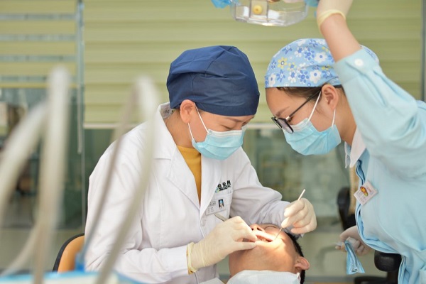 Two dentists are digging into a patient's teeth and examining in a dental hospital, which is occupied by dental care equipment.
